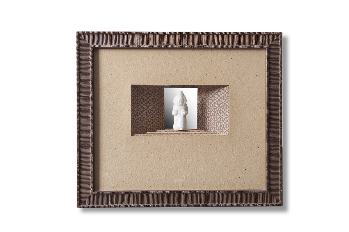 Statuette blanche placée dans une niche, cadre en carton cannelé